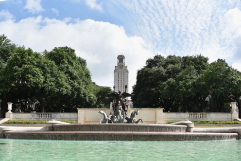 A fountain is in front of the University of Texas tower.