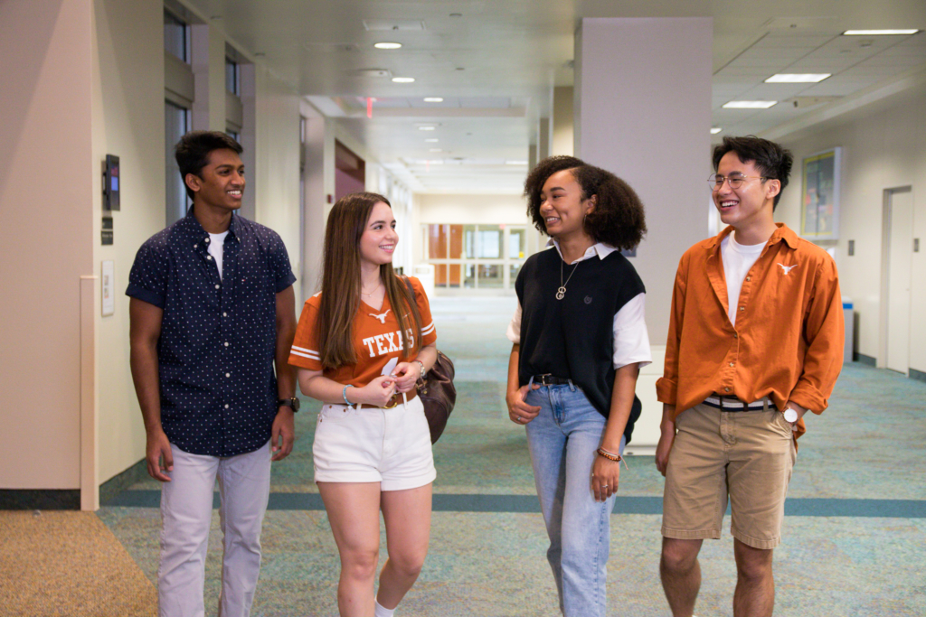 Four students walk together in a hallway of San Jacinto Hall
