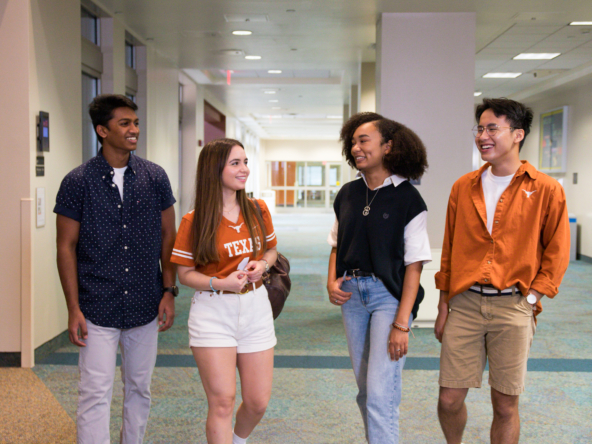 Four students walk together in a hallway of San Jacinto Hall