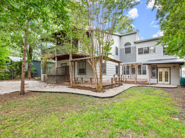 Back of house and large backyard with trees and grass