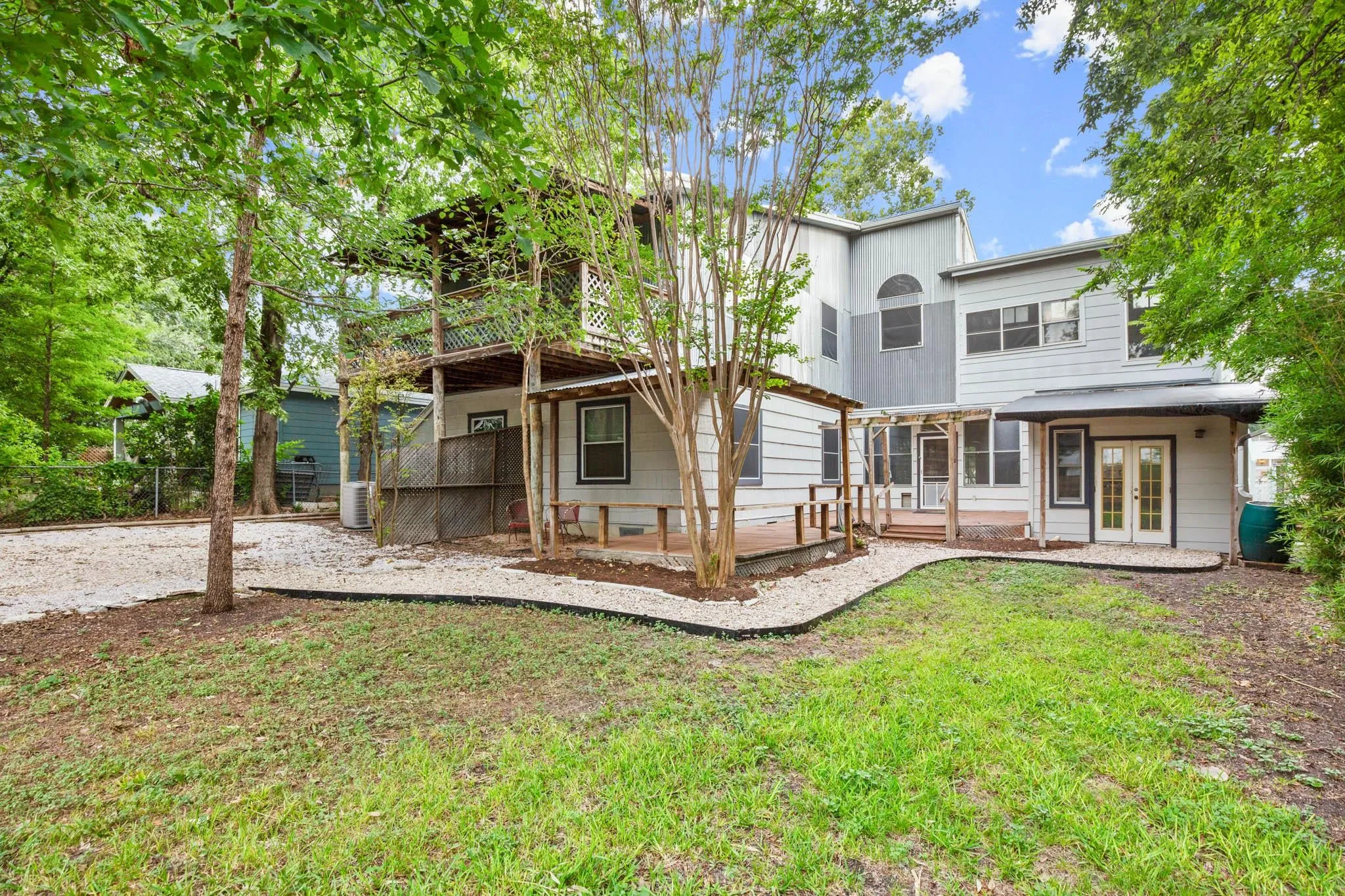 Rear view of property with french doors, a wooden deck, and a patio area