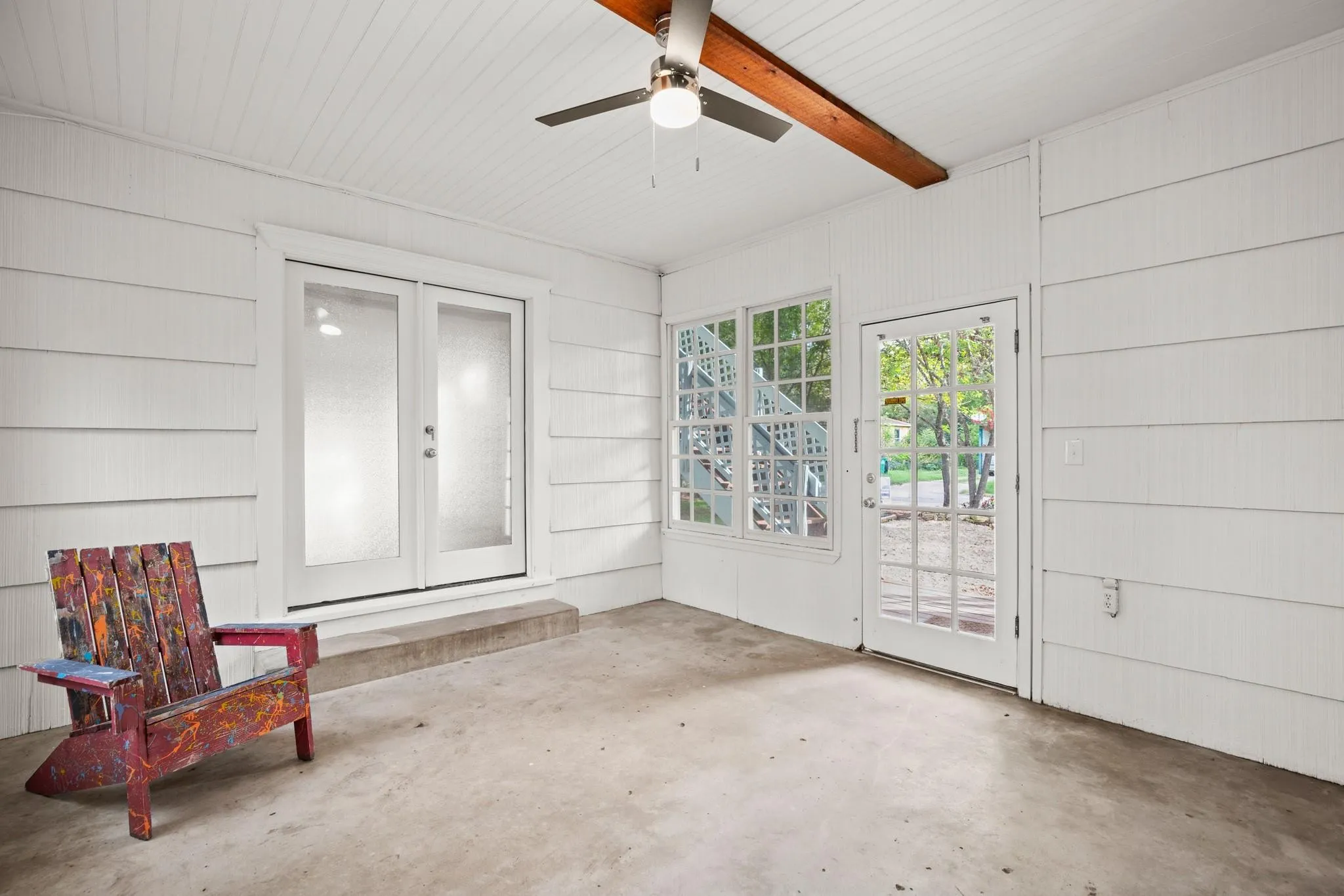 Unfurnished sunroom with french doors, DOG door, ceiling fan, and a patio area