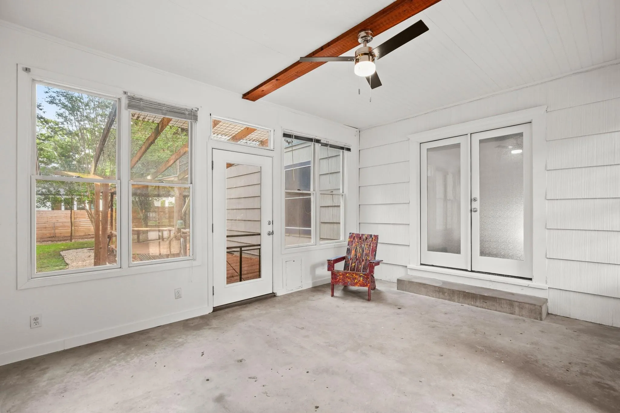 Unfurnished sunroom featuring a ceiling fan, DOG door, a patio, and french doors